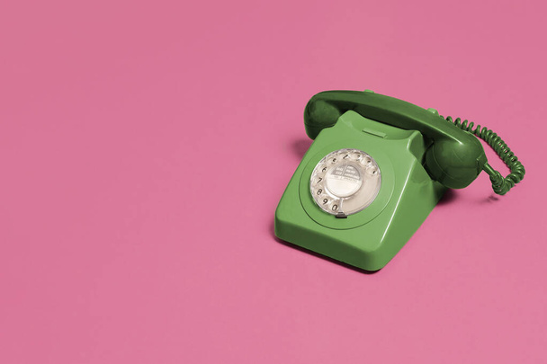 Vintage antique green rotary phone on a pink background with copy space and room for text with a right side composition. - Fotó, kép