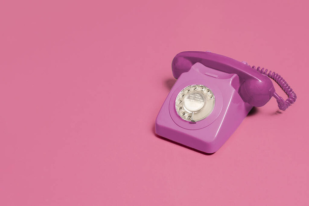 Vintage αντίκες ροζ περιστροφικό τηλέφωνο σε ένα ροζ φόντο με αντίγραφο χώρο και χώρο για κείμενο με σύνθεση δεξιά πλευρά. - Φωτογραφία, εικόνα