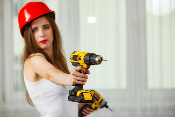 Young woman using power driil for work at home. Girl working at flat remodeling. Building, repair and renovation. - Φωτογραφία, εικόνα