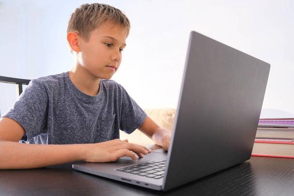 Niño preadolescente usando computadora portátil en casa. Tecnología, aprendizaje en línea, educación a distancia, estudio en el hogar, tareas, juegos educativos para niños
 - Foto, Imagen