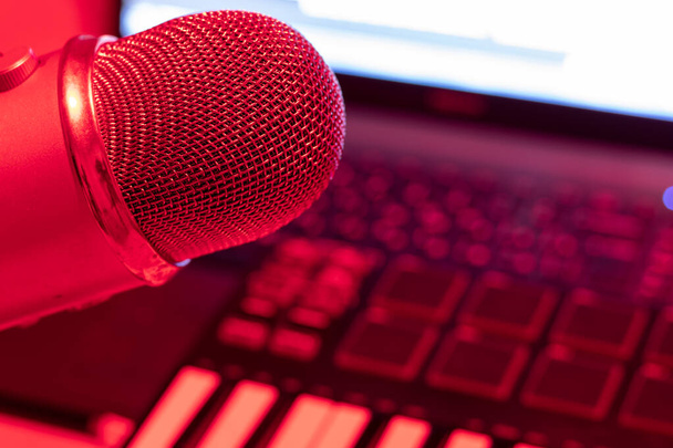 Home Studio kondenzátor professzionális mikrofon és zongora billentyűzet. Laptop piros fényben. - Fotó, kép