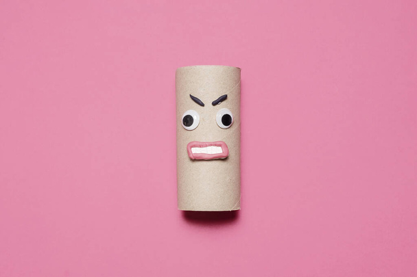 Θυμωμένος άδειο ρολό του χαρτιού υγείας με googly μάτια, στόμα, και τα φρύδια σε ένα ροζ φόντο με αντίγραφο χώρο και χώρο για κείμενο - Φωτογραφία, εικόνα