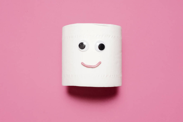 Rouleau plein de papier toilette joyeux et souriant avec les yeux et la bouche googly sur un fond rose avec l'espace de copie et la pièce pour le texte
 - Photo, image