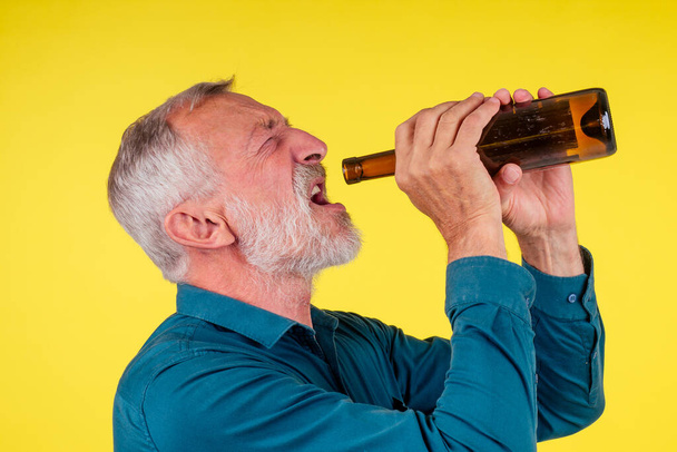 старший чоловік п'є алкоголь сам студія жовтий фон
 - Фото, зображення