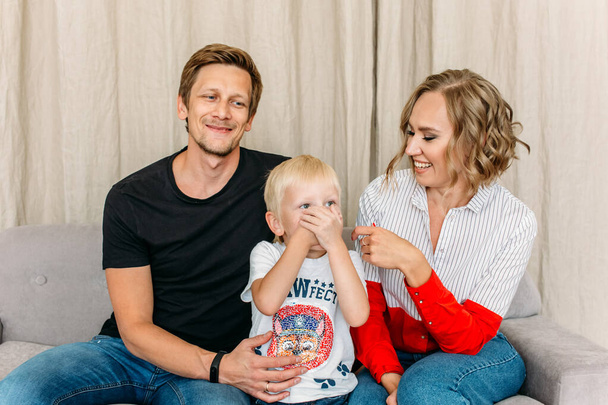 happy family, mom dad and little son in a bright room, they laugh, hug, baby hugs parents - Valokuva, kuva