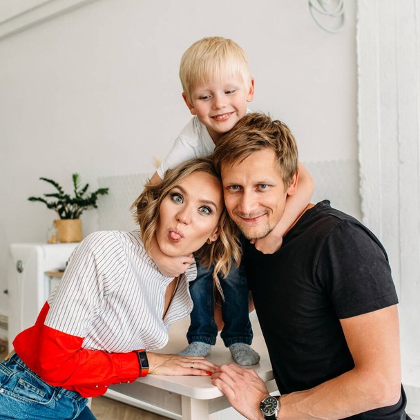 happy family, mom dad and little son in a bright room, they laugh, hug, baby hugs parents - Valokuva, kuva