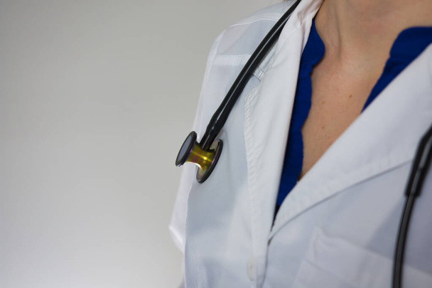 Imagen de cerca de la bata blanca y el estetoscopio sobre el trabajador médico aislado sobre fondo gris
 - Foto, Imagen