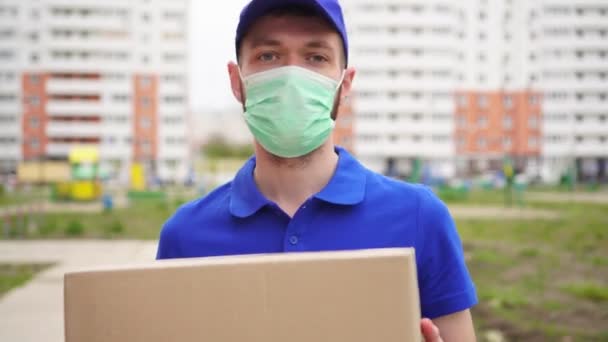 Man koerier bezorger met een medisch masker op zijn gezicht - Video