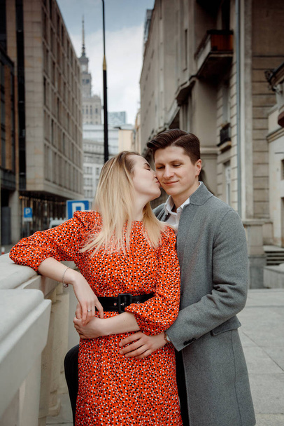 tourist couple in big city. The guy with the girl is hugging and happy. Girl in red dress kissing boy.The guy in the headset - Fotografie, Obrázek