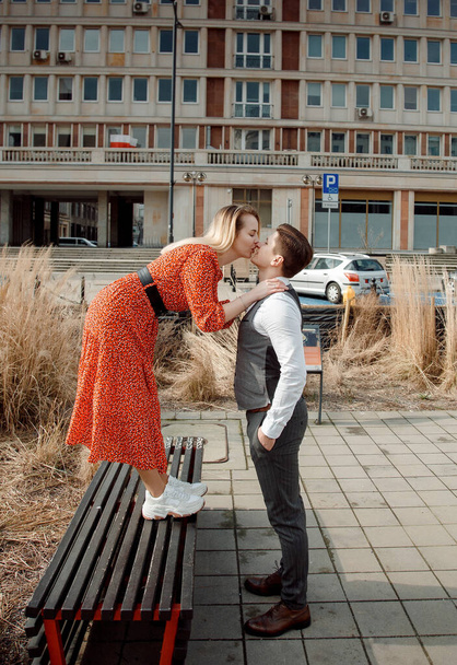 turisti pari suurkaupungissa. Mies tytön kanssa halaa ja on onnellinen. Tyttö punainen mekko suudella boy.The kaveri kuulokkeet
 - Valokuva, kuva