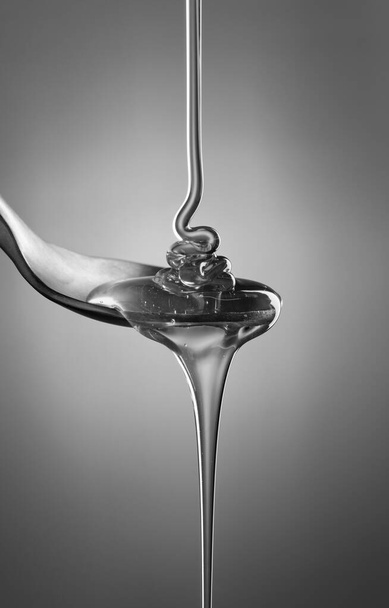 ПИТАНИЕ: студия натюрморт из меда наливают в чайную ложку
 - Фото, изображение