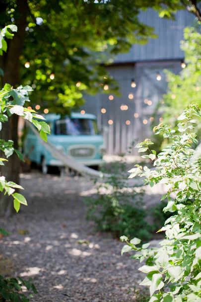 Размытый фон с деревьями, синий винтажный фургон Camper и легкая гирлянда
 - Фото, изображение