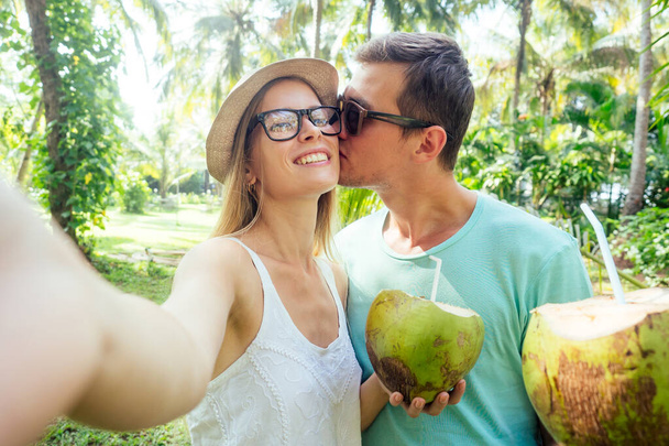 Young loving couple drink coconut taking selfie pictures photo on camera smatrphone - Foto, immagini