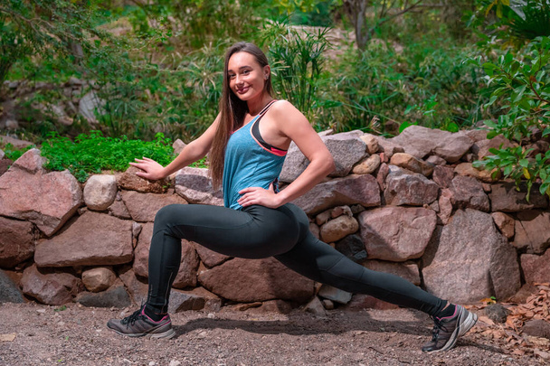 Genç bir kadın parkta yoga yapıyor ve eğitiyor. Açık hava kadınlarının sporu - Fotoğraf, Görsel