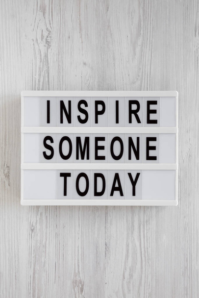 'Inspire someone today' words on a modern board on a white wooden background, top view. Overhead, from above, flat lay. Close-up. - Фото, зображення