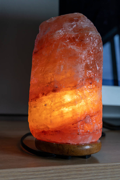 Bir bilgisayar masasında duran pembe turuncu bir Himalaya tuz lambası. İş yerinde sakinleştirici kavram - Fotoğraf, Görsel