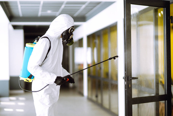 Disinfecting of office to prevent COVID-19, Man in protective hazmat suit with  with spray chemicals to preventing the spread of coronavirus, pandemic in quarantine city. Cleaning concept. - Zdjęcie, obraz