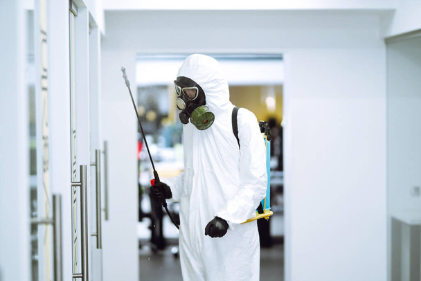Disinfecting of office to prevent COVID-19, Man in protective hazmat suit with  with spray chemicals to preventing the spread of coronavirus, pandemic in quarantine city. Cleaning concept. - Photo, image