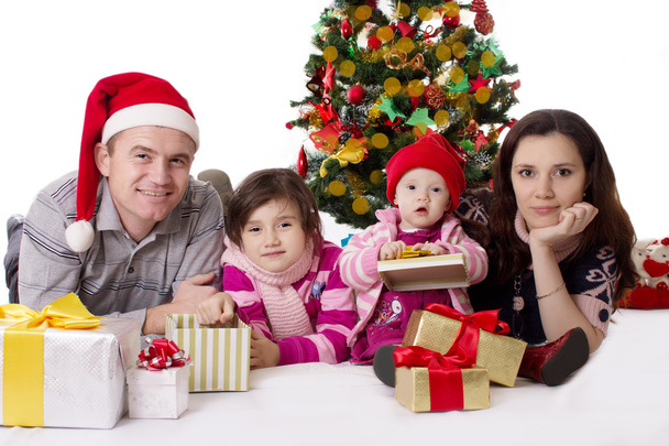 οικογένεια με δύο μικρές κόρες που βρίσκεται κάτω από το χριστουγεννιάτικο δέντρο - Φωτογραφία, εικόνα