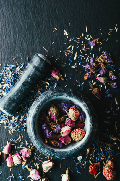 Colheita de ervas medicinais, Ayurveda, medicina alternativa, flores secas em uma argamassa de mármore em um fundo preto
 - Foto, Imagem