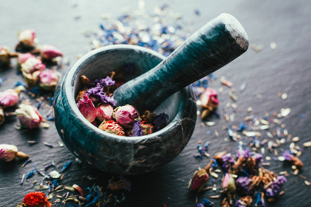 Cosecha de hierbas medicinales, Ayurveda, medicina alternativa, flores secas en un mortero de mármol sobre un fondo negro
 - Foto, Imagen