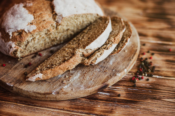Getreidehandwerk Brotlaib. Rustikaler Laib selbstgebackenes Brot auf dunklem Holztisch. Hausgemachtes Brot mit Gewürzen. Aus der Vogelperspektive. Richtiger Ort für den Test - Foto, Bild