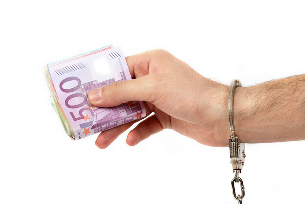 Male hand with handcuffs holding a lot of money - Foto, immagini