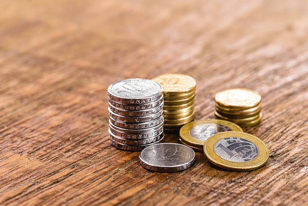 Münzen aus Brasilien, Stapel von 1 echten Münzen, 50 Cent und anderen Werten. Münzen von einem echten und fünfzig Cent von Brasilien auf Holzgrund. Persönliche Ersparnisse oder Reservekonzept. - Foto, Bild