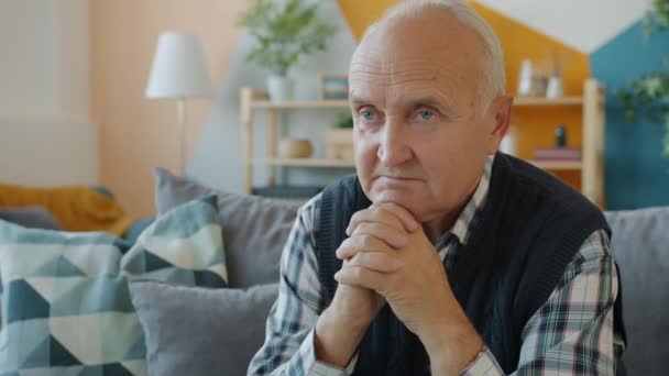 Slow motion of lonely senior man sitting in apartment alone thinking with thoughtful face - Filmmaterial, Video