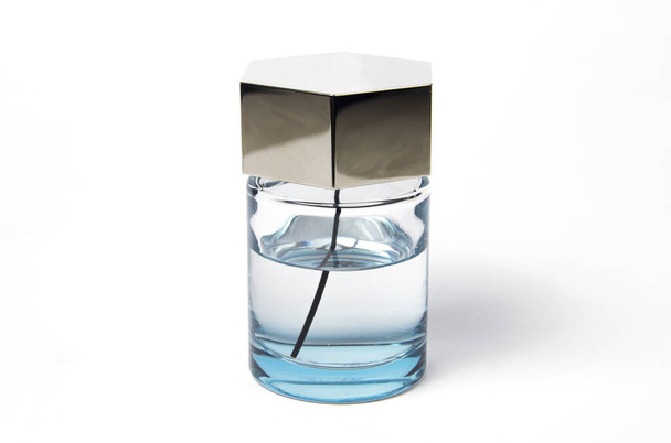 Духи воды на белом фоне. Стеклянная бутылка с голубой жидкостью
 - Фото, изображение
