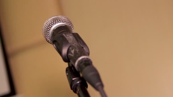 Acercamiento en un micrófono de condensador dinámico en un soporte en un escenario grande. Dolly disparó. Enfoque selectivo con espacio de copia
. - Metraje, vídeo
