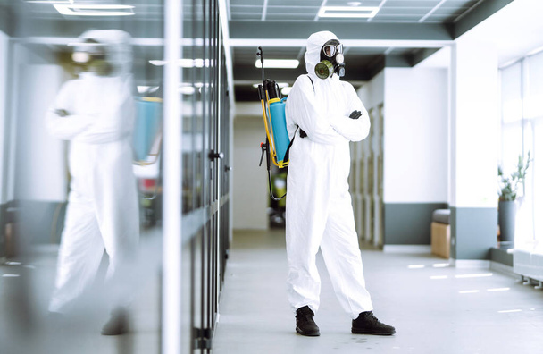 Man in protective hazmat suit in an empty office. Concepts to preventing the spread of coronavirus, pandemic in quarantine city. Covid -19. - Фото, изображение