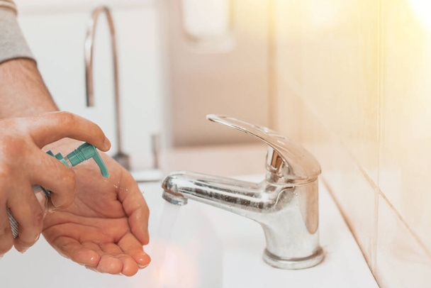 Чоловік у громадському місці миє руки в раковині. Вичавити антибактеріальне мило рук. Запобіжні заходи та захист від коронавірусу
. - Фото, зображення