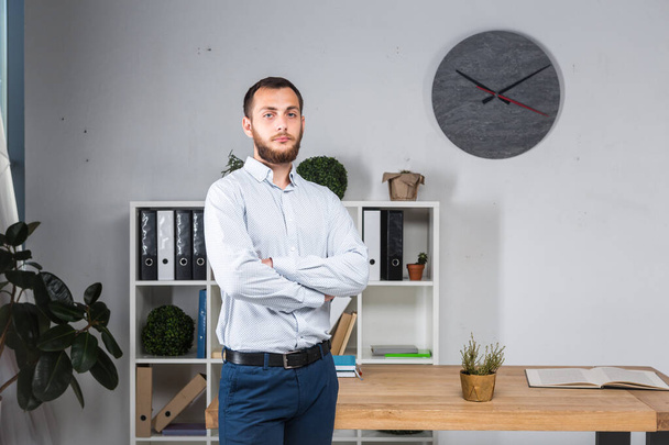 Confidence looks great on him. Business Man With Beard At Modern Office. Profession concept. Leadership. Successful stylish young bearded man in casual shirt standing in the office. - Foto, afbeelding