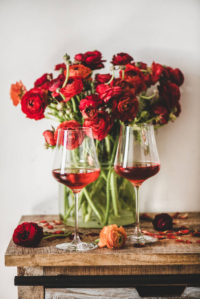 Shades of Rose. Rose wine of different colors in glasses and red spring blossom flowers over wooden table background. Wine shop, bar, wine tasting, wine list concept - Foto, Imagen