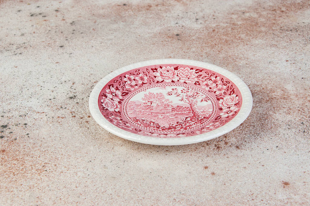 Antyczne porcelanowe czerwone danie na betonowym tle. Kopiuj miejsce na tekst, rekwizyty fotograficzne żywności. - Zdjęcie, obraz
