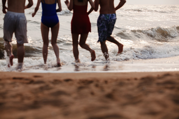 Amigos corriendo al agua en una playa de arena
 - Foto, imagen