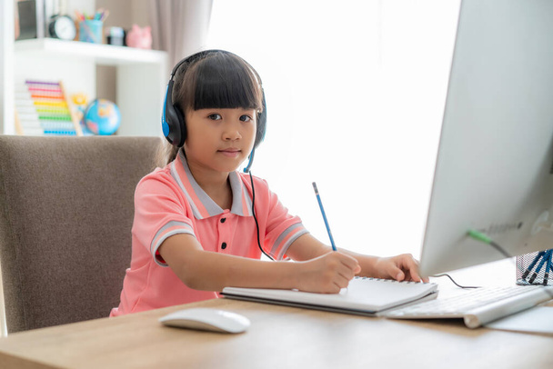 Aasialainen tyttö opiskelija videoneuvottelu e-oppiminen opettajan kanssa tietokoneella olohuoneessa kotona. Kotikoulu ja etäopetus, verkko, koulutus ja internet suojaavat COVID-19-viruksilta. - Valokuva, kuva