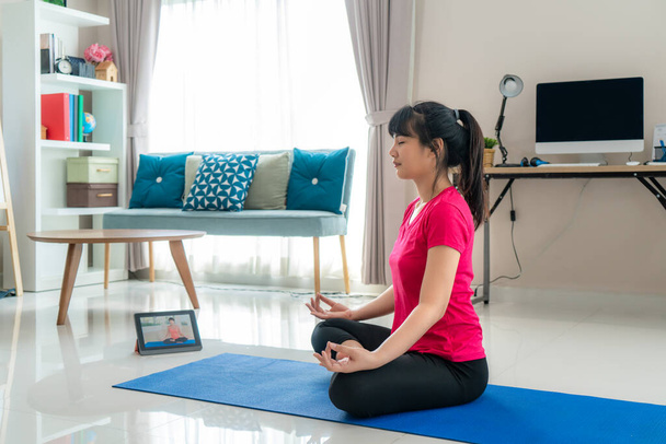 Азійська жінка робить вправи з йоги, щоб відійти від комп'ютерів, щоб зробити перерви в середині дня через уроки відеоігор на цифрових планшетах під час роботи з дому.. - Фото, зображення