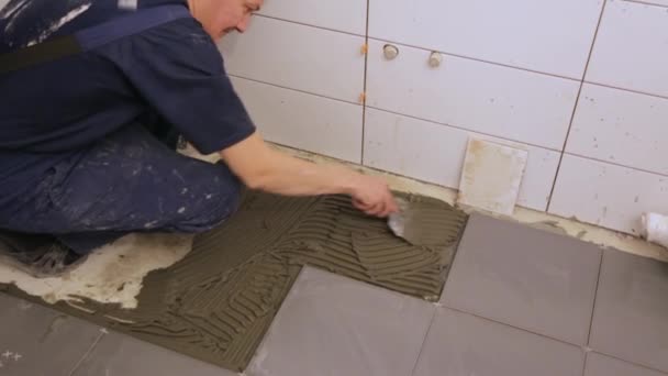Csempe ragasztót a padlóra rakó munkás - Felvétel, videó