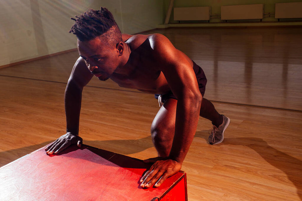 afro man pushing up on the floor in dark light gym in evening - Φωτογραφία, εικόνα