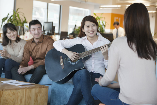 Ufficio lavoratore suonare la chitarra ai colleghi
 - Foto, immagini