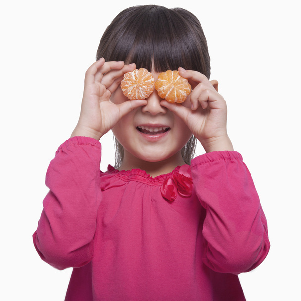 Petite fille tenant des mandarines devant ses yeux
 - Photo, image