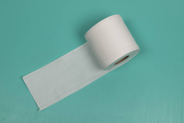 Hygiene item in the bathroom. Toilet paper holder. Soft tissue roll isolated on green background. - Photo, Image