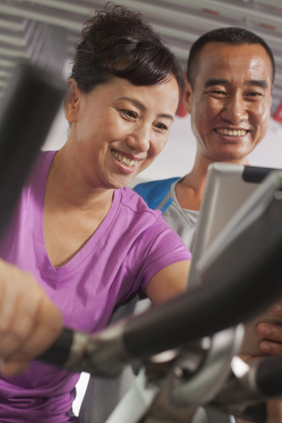 Woman exercising on the exercise bike with her trainer - Photo, Image