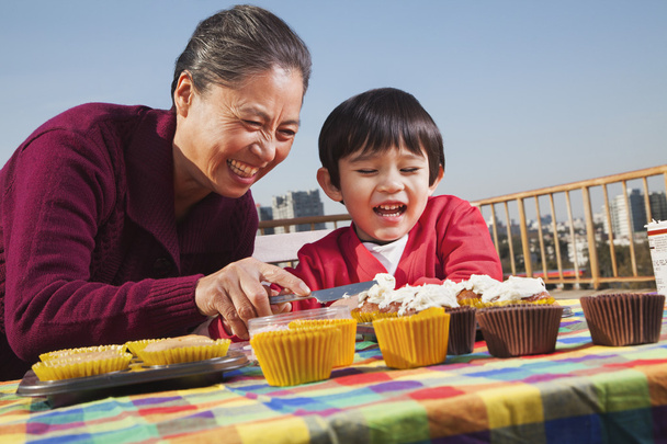 Abuela y nieto decorando cupcakes
 - Foto, Imagen