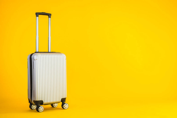 Gri renkli valiz ya da bagaj çantası kullanımı sarı izole arka planda seyahat ve boş zaman için - Fotoğraf, Görsel
