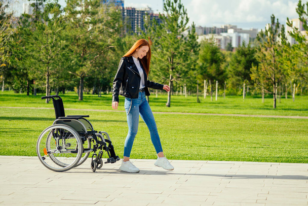 redhaired ginger woman making first steps after long recovery.she walking without her wheelchair in spring park - Фото, зображення