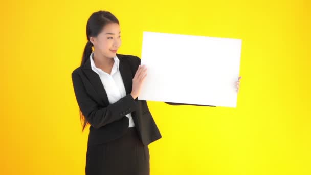 felvétel gyönyörű ázsiai üzletasszony fekete öltönyben kezében üres papírt elszigetelt sárga - Felvétel, videó