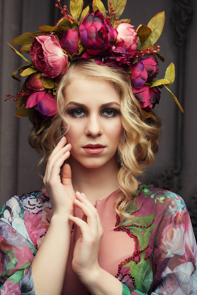 Charming blonde with a floral wreath dressed in a chic dress with floral patterns - Foto, immagini